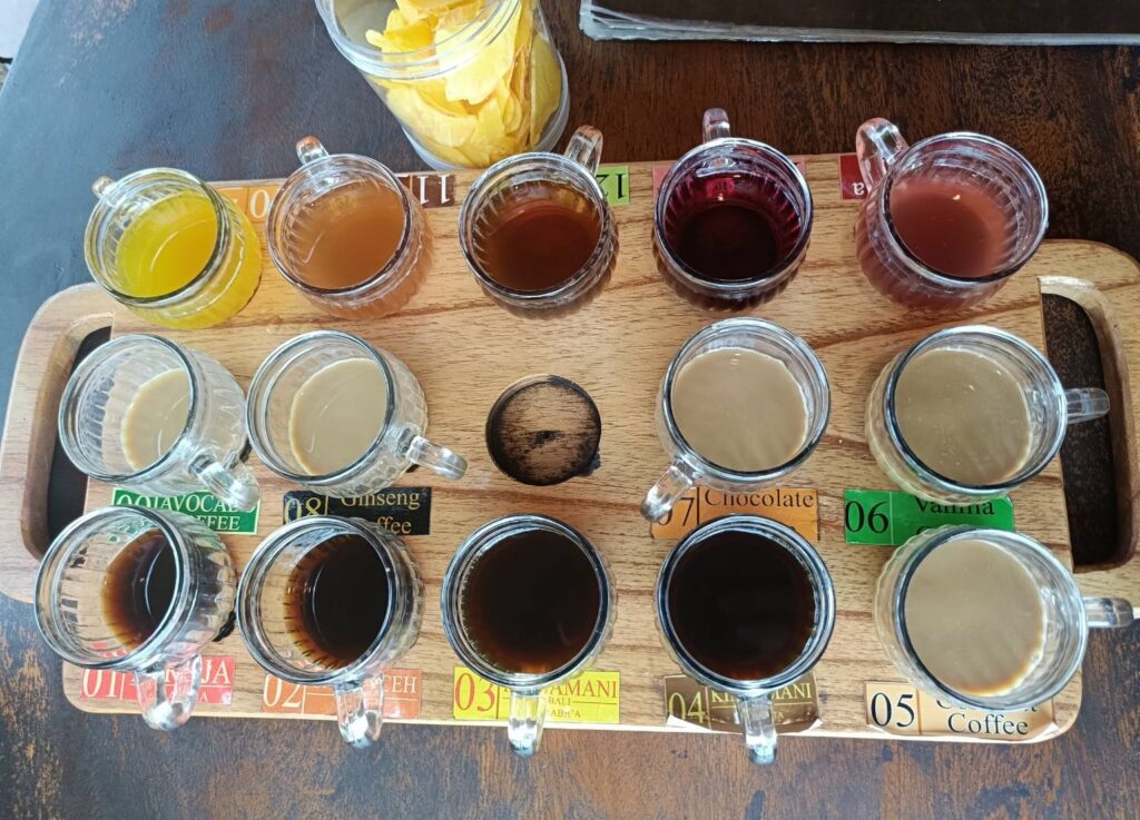 木のトレーに並んだバリ島のコーヒー飲み比べセット。番号ラベル付きのグラスが14杯