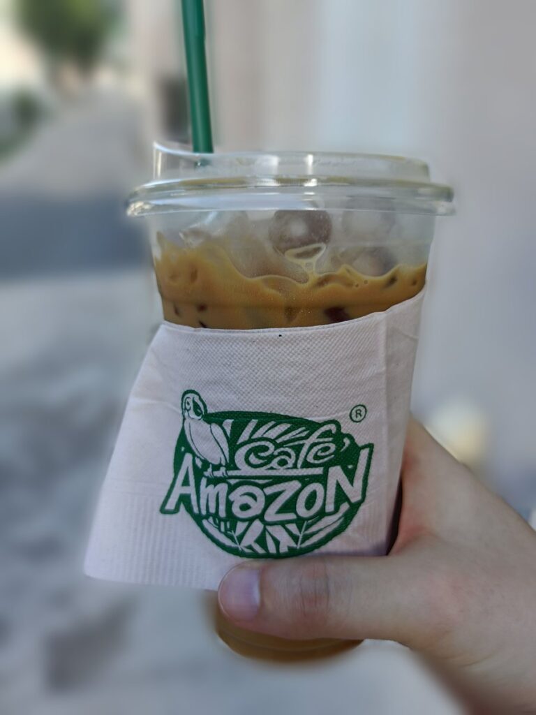 タイのカフェアマゾンで買ったアイスコーヒー「Amazon」。カップにロゴ入りの紙ナプキンが巻かれている